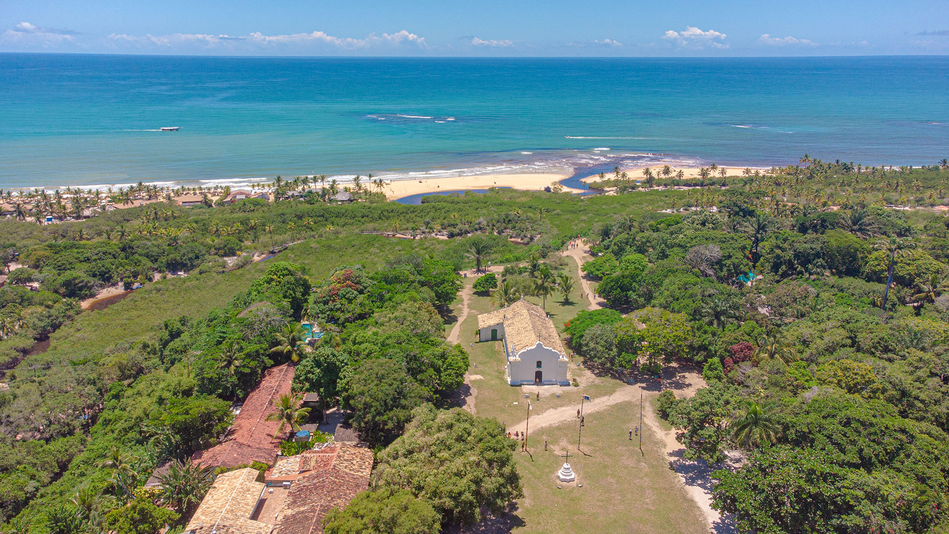 Vista aérea do Quadrado de Trancoso, com a igreja histórica, o mar e a praia ao fundo